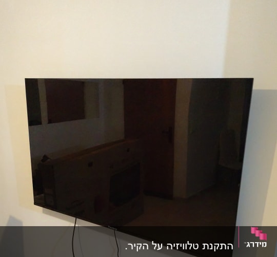 טלוויזיה תלויה על הקיר עם כבלים חשמליים